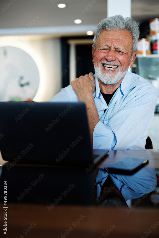 A senior man with gray hair and a beard has an online class on his laptop in the living room. A senior man with gray hair and a beard has an online class on his laptop in the living room.