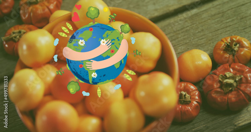Image of arms wrapped around planet earth over fresh tomatoes