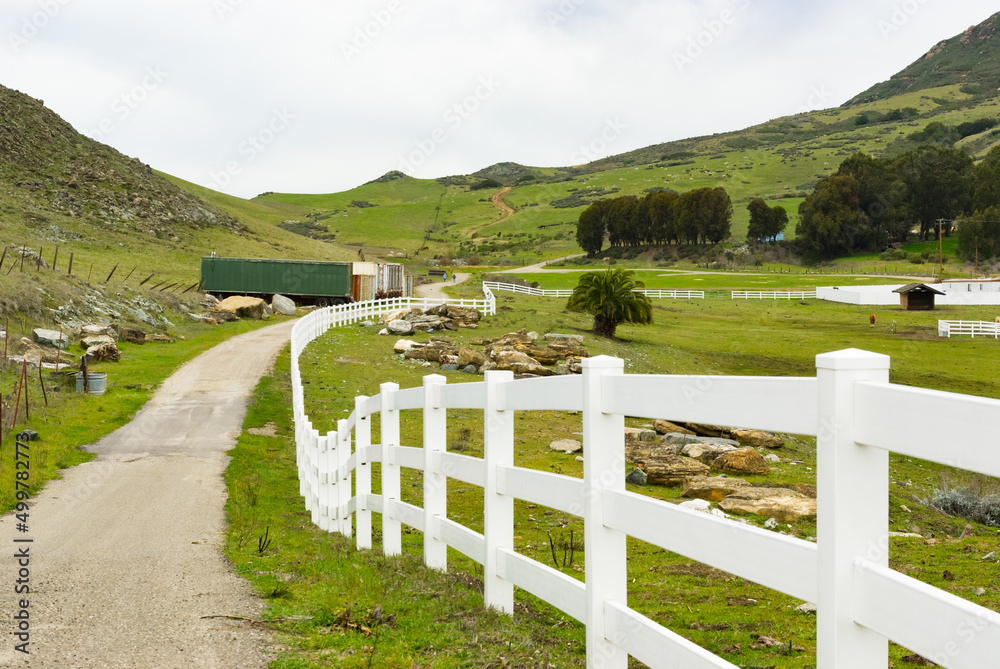 Narrow farm road with white picket fence