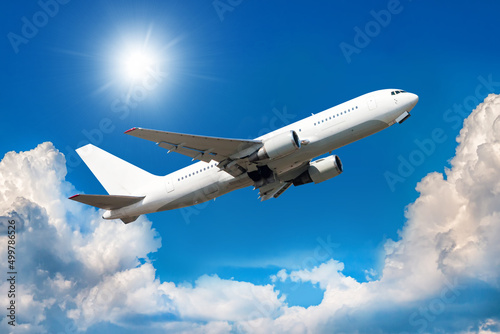 White wide body passenger aircraft is climbing in the air above scenic clouds
