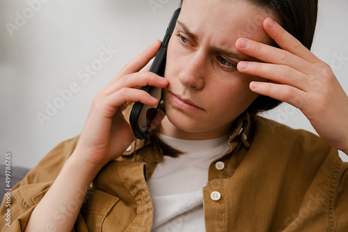 Close up of Compassionate millennial lady support friend by cell try to help ponder on advice. Sad young woman has difficult phone talk hold gadget by ear listen to unexpected bad news think on answer