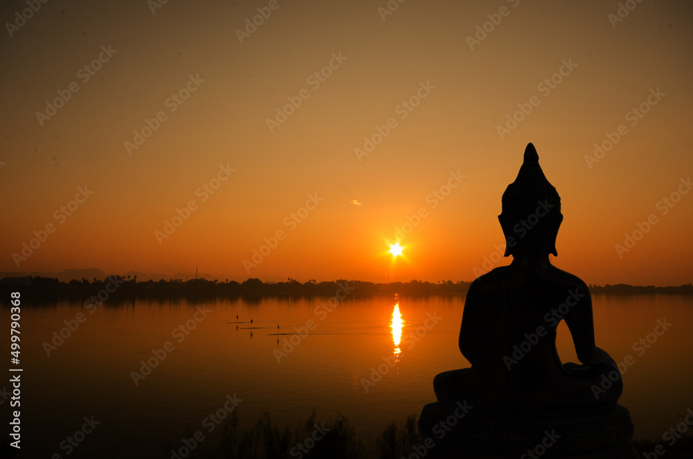 Silhouette buddha on sunset background.