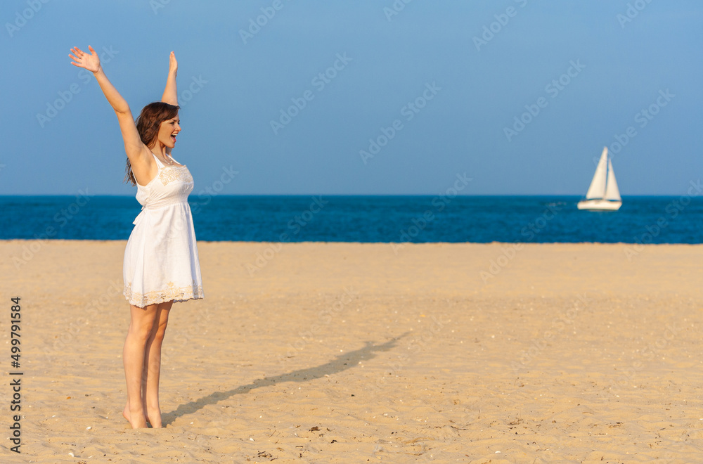 Girl Young Woman Standing Arms Raised in Celebration on Beach With Sail Boat at Sea Girl Young Woman Standing Arms Raised in Celebration on Beach With Sail Boat at Sea