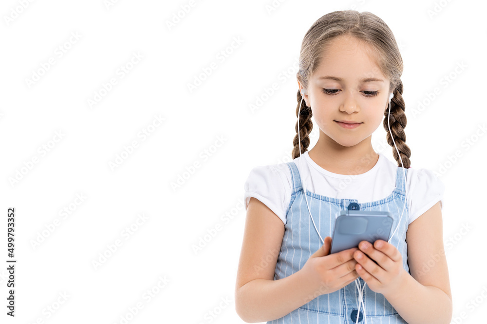 positive girl in wired earphones using mobile phone isolated on white. positive girl in wired earphones using mobile phone isolated on white.