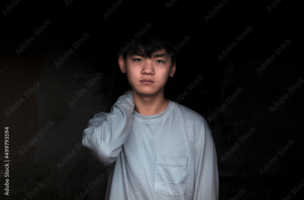 Portrait of Asian teenage boy against black background
