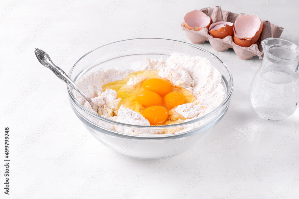 Kneading the dough for bakery product. Adding eggs into yeast dough in the glass bowl. Preparing buns, Easter cake or pie. Step by step recipe. Step 4 Kneading the dough for bakery product. Adding eggs into yeast dough in the glass bowl. Preparing buns, Easter cake or pie. Step by step recipe. Step 4