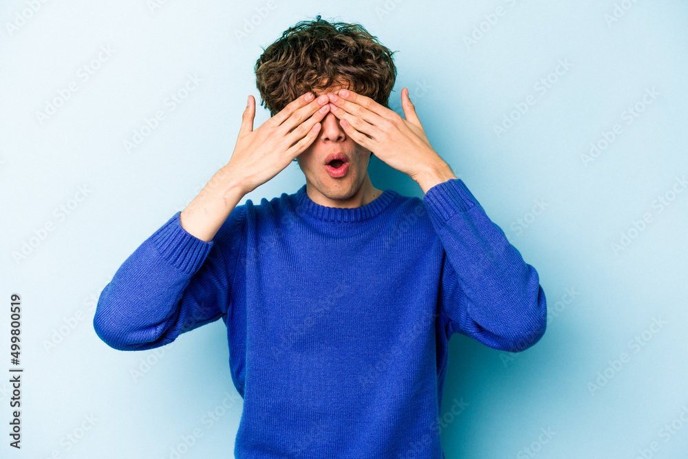 Young caucasian man isolated on blue background afraid covering eyes with hands. Young caucasian man isolated on blue background afraid covering eyes with hands.