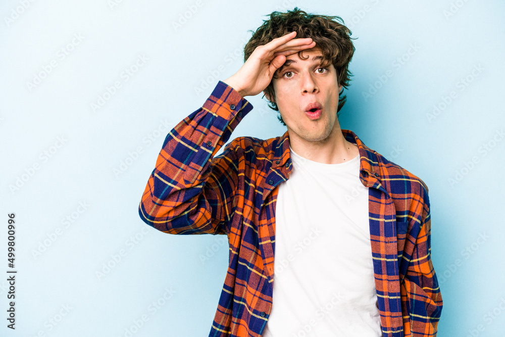 Young caucasian man isolated on blue background looking far away keeping hand on forehead. Young caucasian man isolated on blue background looking far away keeping hand on forehead.