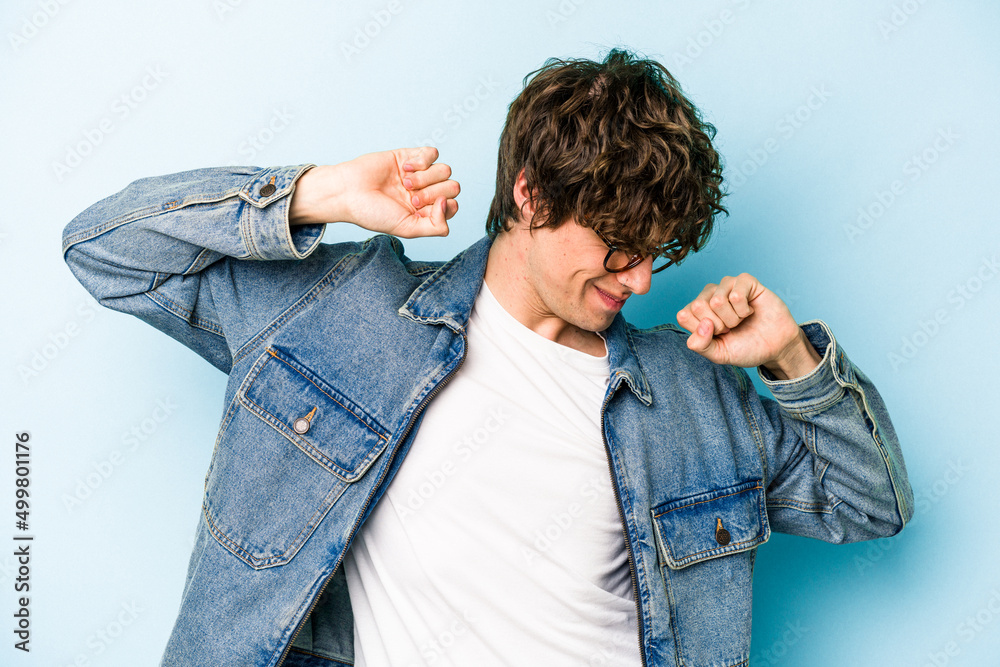 Young caucasian man isolated on blue background stretching arms, relaxed position. Young caucasian man isolated on blue background stretching arms, relaxed position.