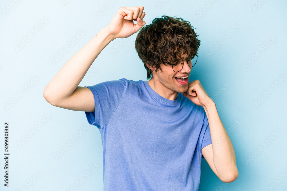 Young caucasian man isolated on blue background celebrating a special day, jumps and raise arms with energy. Young caucasian man isolated on blue background celebrating a special day, jumps and raise arms with energy.