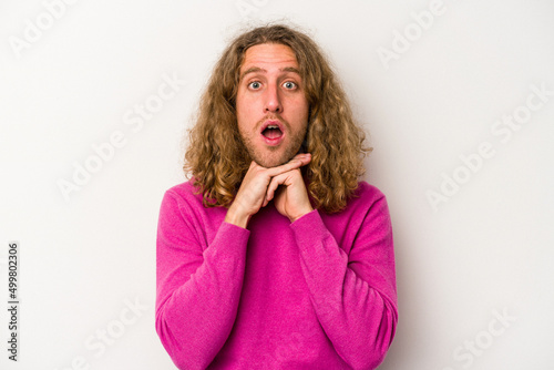 Young caucasian man isolated on white background praying for luck, amazed and opening mouth looking to front.