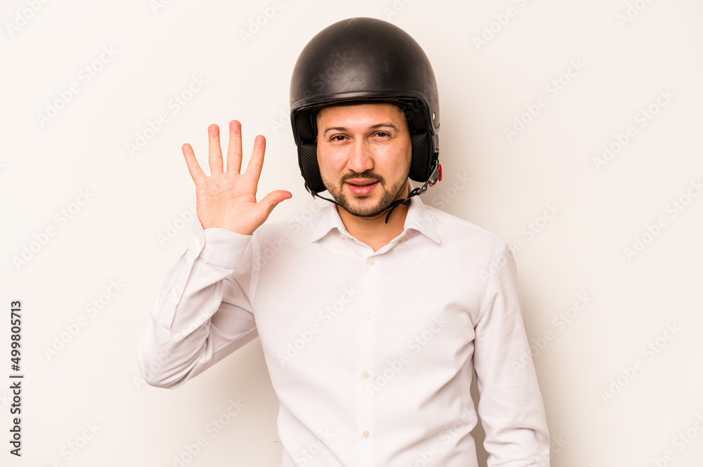 Hispanic business man going to work with motorcycle isolated on white background smiling cheerful showing number five with fingers. Hispanic business man going to work with motorcycle isolated on white background smiling cheerful showing number five with fingers.