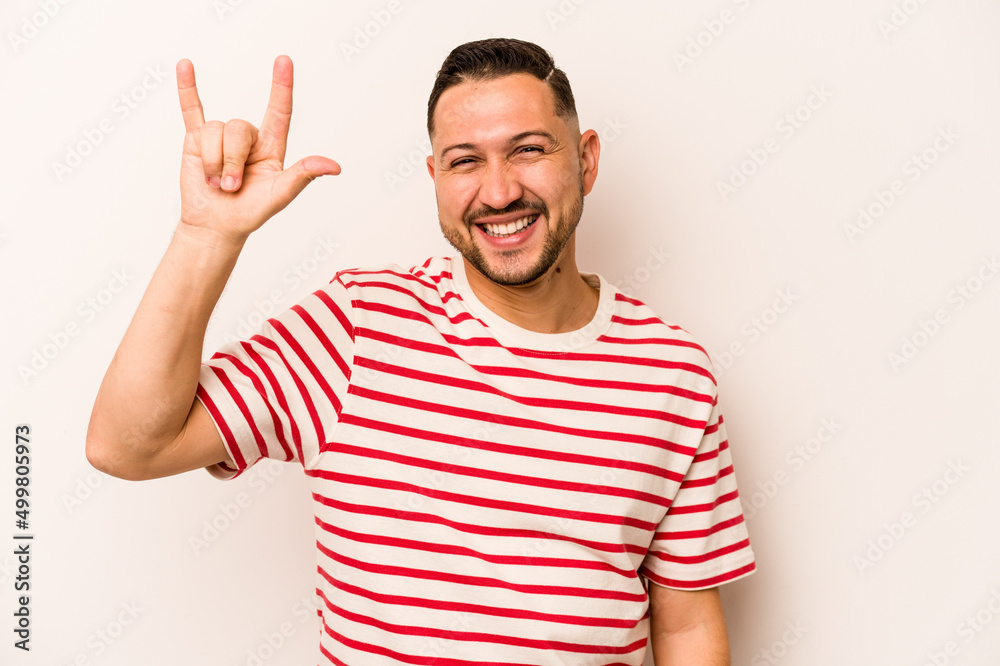 Young hispanic man isolated on white background showing a horns gesture as a revolution concept. Young hispanic man isolated on white background showing a horns gesture as a revolution concept.