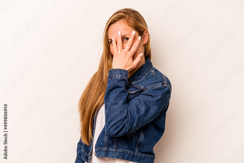 Young caucasian woman isolated on white background blink at the camera through fingers, embarrassed covering face. Young caucasian woman isolated on white background blink at the camera through fingers, embarrassed covering face.