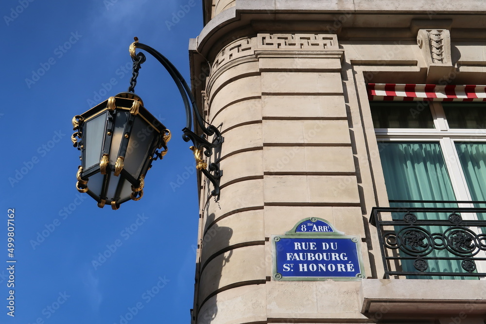 Plaque de rue de la prestigieuse rue du Faubourg Saint Honoré dans la ville de Paris, adresse du palais de l’Élysée, d'ambassades et de boutiques de luxe, avec un réverbère ancien (France) - obrazy, fototapety, plakaty 
