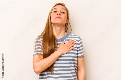 Young caucasian woman isolated on white background taking an oath, putting hand on chest.