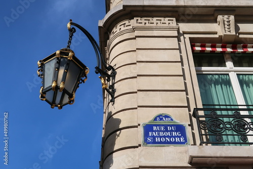 Fototapeta Naklejka Na Ścianę i Meble -  Plaque de rue de la prestigieuse rue du Faubourg Saint Honoré dans la ville de Paris, adresse du palais de l’Élysée, d'ambassades et de boutiques de luxe, avec un réverbère ancien (France)