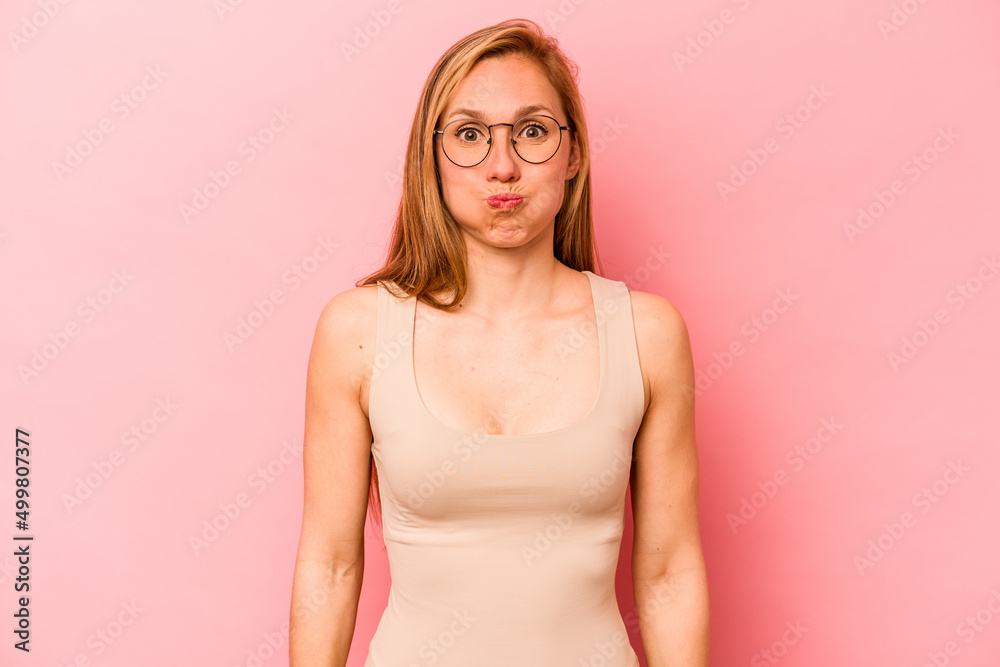 Obraz premium Young caucasian woman isolated on pink background blows cheeks, has tired expression. Facial expression concept.