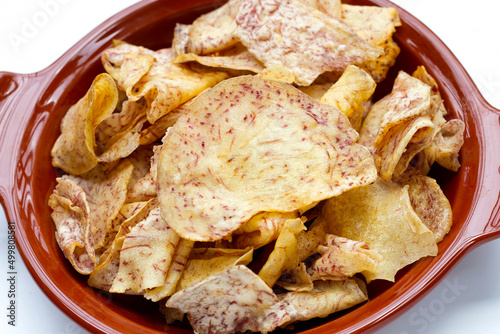 Crispy taro chips in bowl on white background.