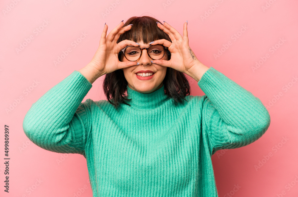 Young caucasian woman isolated on pink background showing okay sign over eyes Young caucasian woman isolated on pink background showing okay sign over eyes