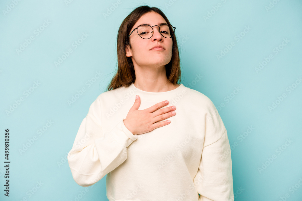 Young caucasian woman isolated on blue background taking an oath, putting hand on chest. Young caucasian woman isolated on blue background taking an oath, putting hand on chest.