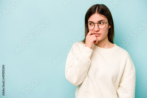 Young caucasian woman isolated on blue background relaxed thinking about something looking at a copy space.