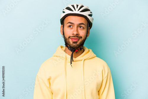 Young hispanic man wearing helmet isolated on blue background dreaming of achieving goals and purposes