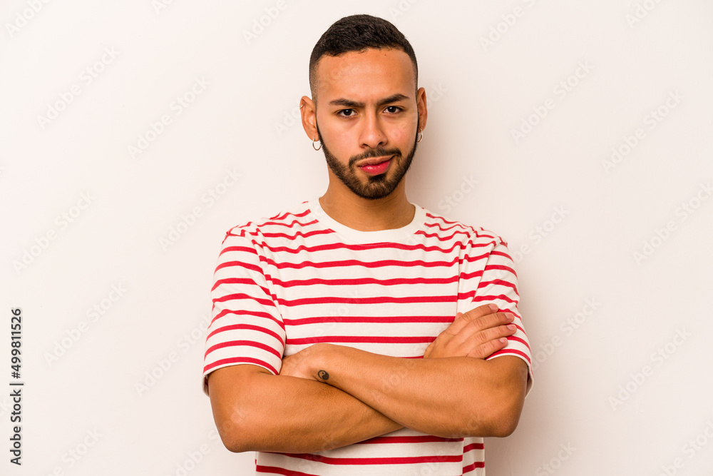 Young hispanic man isolated on white background frowning face in displeasure, keeps arms folded. Young hispanic man isolated on white background frowning face in displeasure, keeps arms folded.
