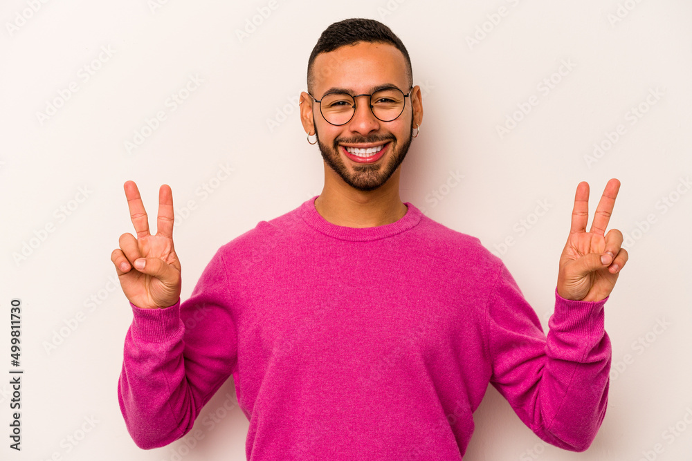 Young hispanic man isolated on white background showing victory sign and smiling broadly. Young hispanic man isolated on white background showing victory sign and smiling broadly.