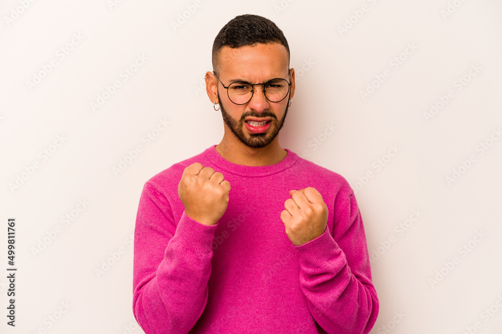 Young hispanic man isolated on white background showing fist to camera, aggressive facial expression. Young hispanic man isolated on white background showing fist to camera, aggressive facial expression.