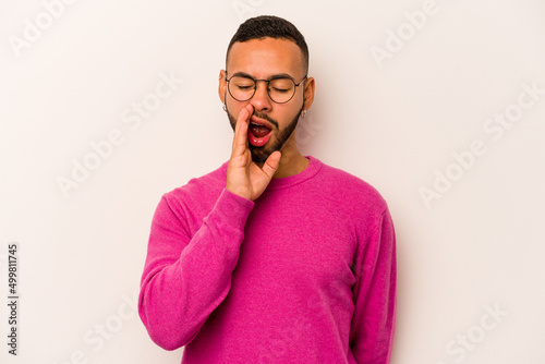Young hispanic man isolated on white background yawning showing a tired gesture covering mouth with hand.