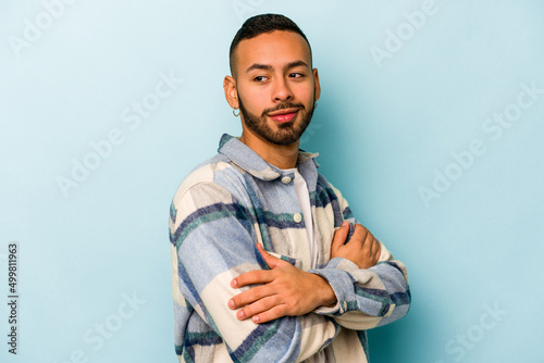 Young hispanic man isolated on blue background laughing and having fun. © Asier
