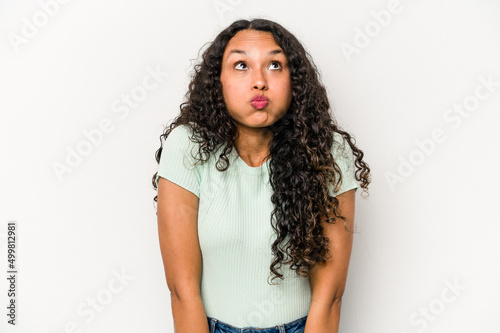 Young hispanic woman isolated on white background shrugs shoulders and open eyes confused.