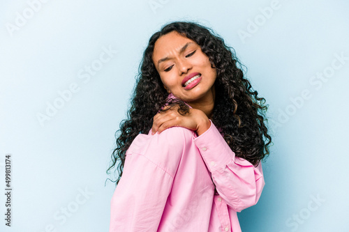 Young hispanic woman isolated on blue background having a shoulder pain.