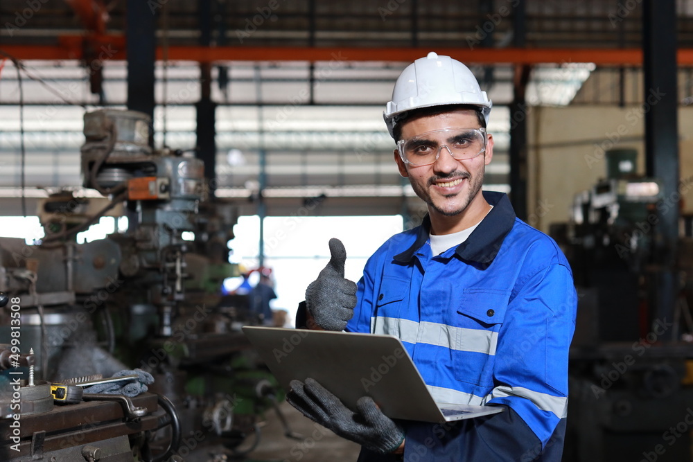 Happy technician engineer worker man in protective suit using computer while showing thumb up and controlling or maintenance operation work lathe metal machine at heavy industry manufacturing factory Happy technician engineer worker man in protective suit using computer while showing thumb up and controlling or maintenance operation work lathe metal machine at heavy industry manufacturing factory