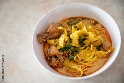Northern Thai Coconut Curry Noodle Soup With Chicken served on table. Khao soi is one of the most popular Thai dishes to eat in northern Thailand, especially in Chiang Mai and Chiang Rai.