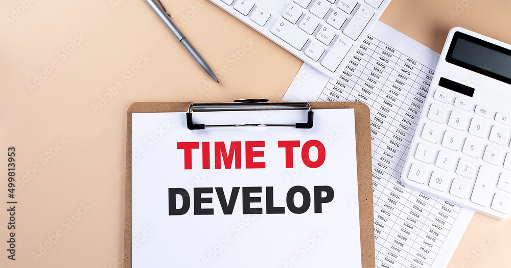 clipboard with white blank paper text TIME TO DEVELOP , keyboard calculator and chart, top view. business concept. clipboard with white blank paper text TIME TO DEVELOP , keyboard calculator and chart, top view. business concept.
