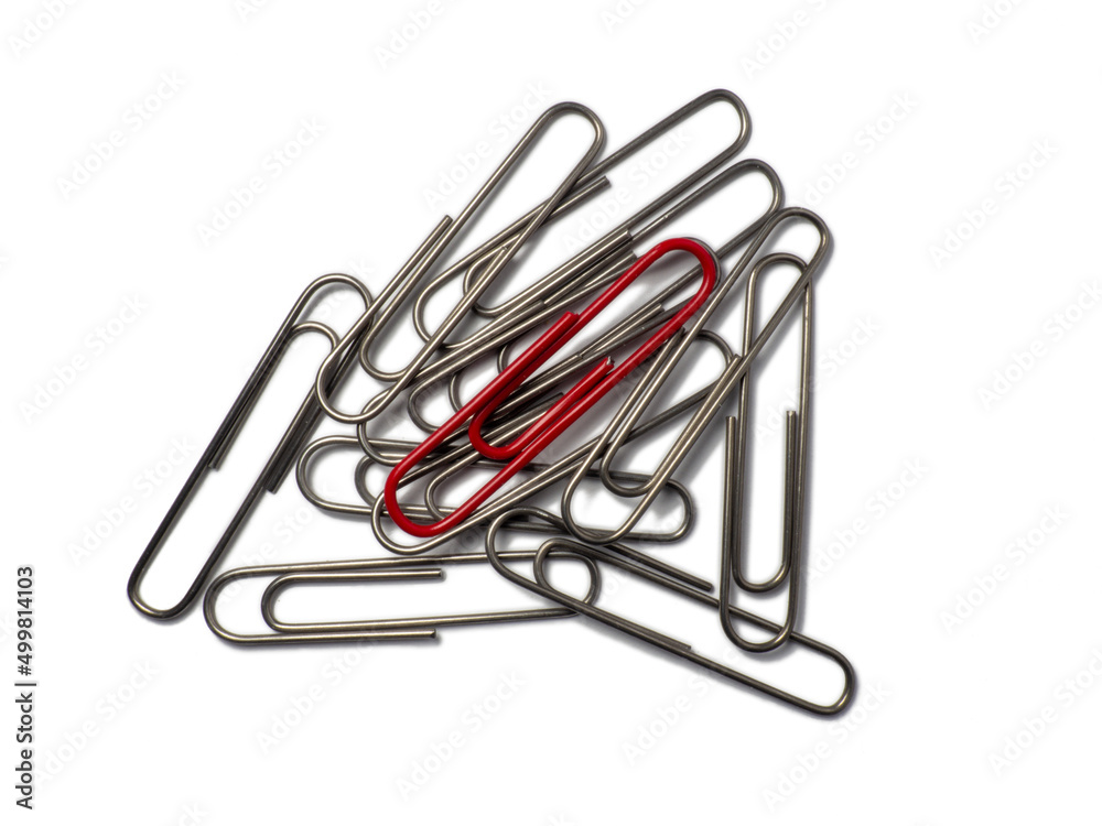 Metal paper clips on a white background. Office supplies isolate. Idea. The concept of loneliness. Confrontation. Stands out from the crowd. Metal paper clips on a white background. Office supplies isolate. Idea. The concept of loneliness. Confrontation. Stands out from the crowd.