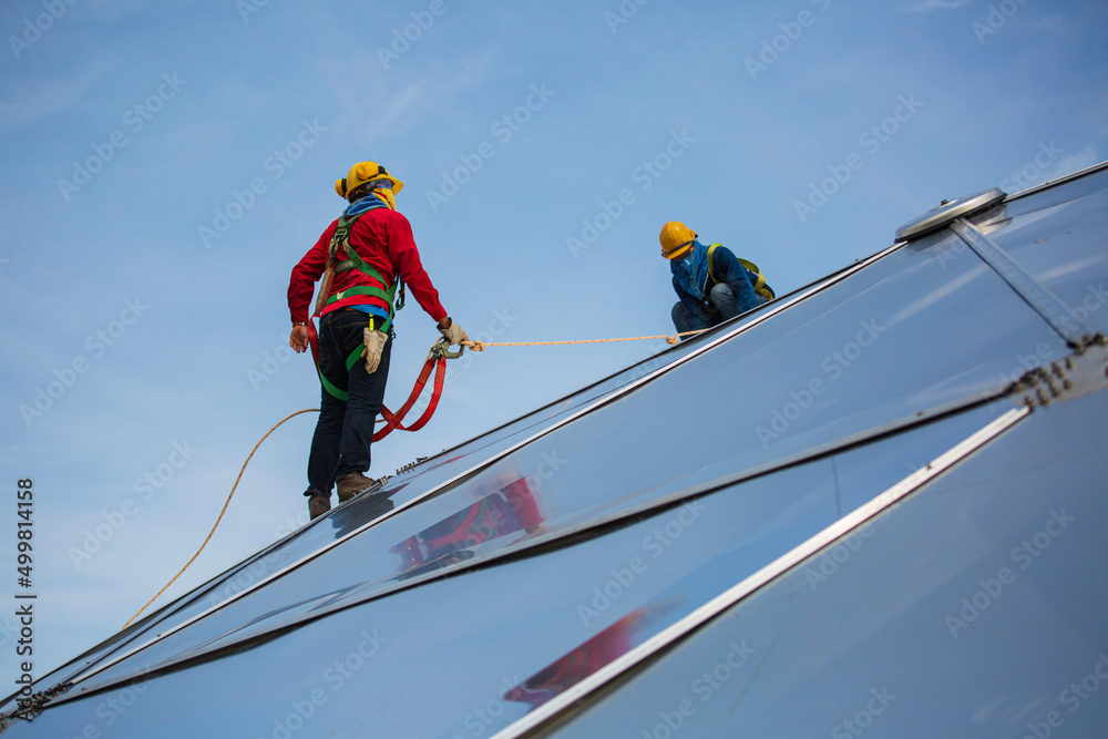 Male two workers rope access height safety connecting with eight knots safety harness, clipping into roof dome construction site oil tank. Male two workers rope access height safety connecting with eight knots safety harness, clipping into roof dome construction site oil tank.