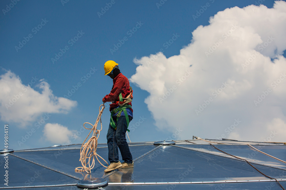 Male workers rope access height safety connecting with eight knots safety harness construction site oil tank dome. Male workers rope access height safety connecting with eight knots safety harness construction site oil tank dome.