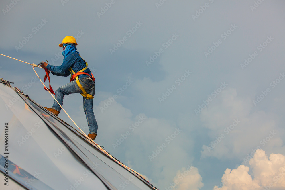 Male workers rope access height safety connecting with a knot safety harness, clipping into roof construction site oil tank dome Male workers rope access height safety connecting with a knot safety harness, clipping into roof construction site oil tank dome