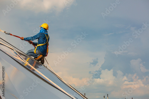 Male workers rope access height safety connecting with a knot safety harness, clipping into roof construction site oil tank dome