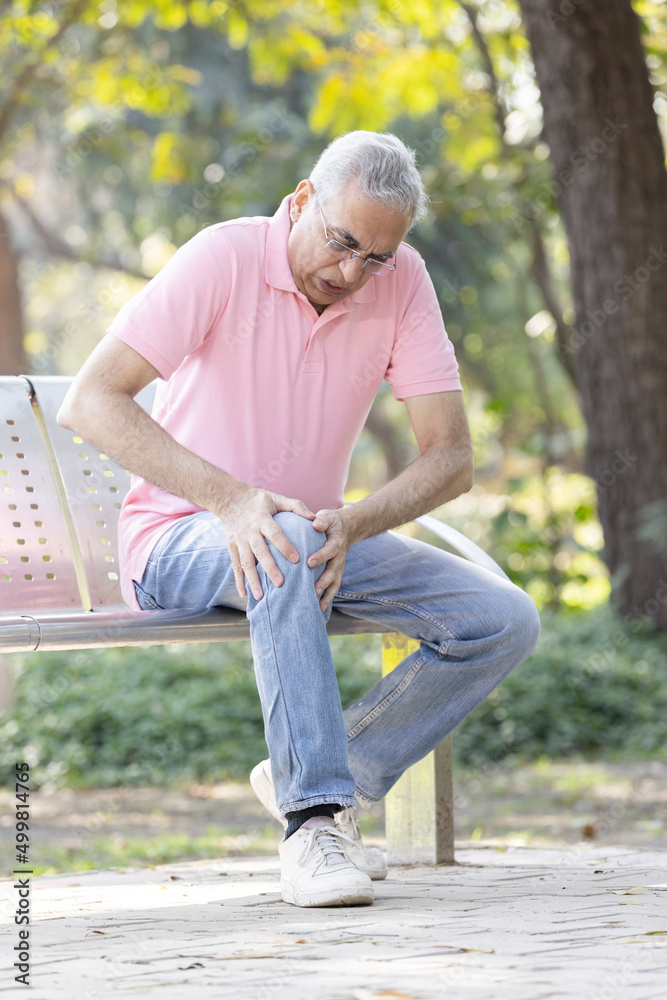 Senior man suffering from knee pain at park Senior man suffering from knee pain at park