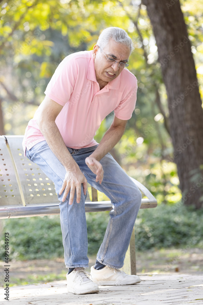 Senior man suffering from knee pain at park Senior man suffering from knee pain at park