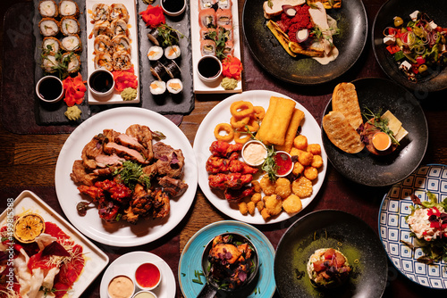 Lots of food on the table. Several restaurant dishes.