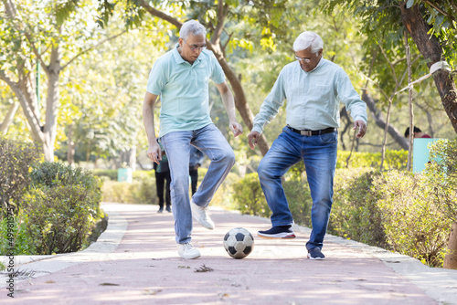 Two senior man having fun while playing football at park