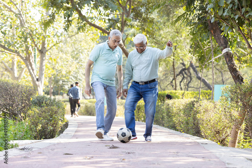 Photography Two senior man having fun while playing football at park