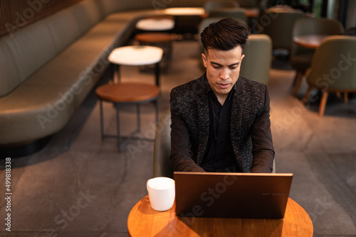 Valokuva Portrait of handsome young businessman using laptop in coffee shop
