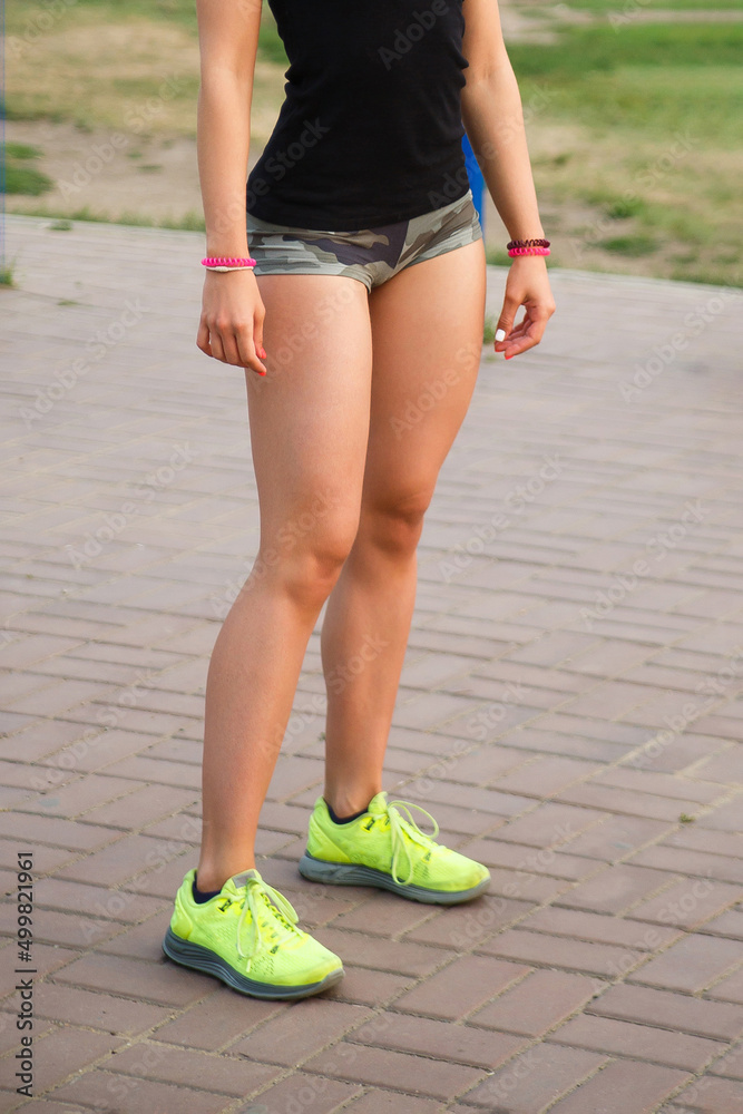 cropped image of female legs. Woman athlete stands in shorts and sneakers