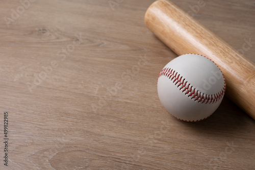 Close up baseball and baseball bat on wooden table background, sport concept